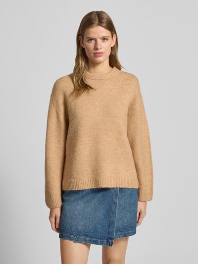 Kobiece modelka nosi Sweter z dzianiny z dodatkiem wełny od Gina Tricot, luźny krój, prążkowane wykończenia, okrągły dekolt, mieszanka materiałów, beżowy odcień, długość tyłu 59 cm, długość rękawów 66 cm, widok całej sylwetki z przodu.