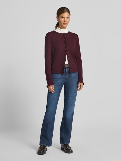 Modelka kobieca nosi kardigan rozpinany Slim Fit Strickjacke aus Schurwoll-Kaschmir-Mix Modell 'ANN' od Brax w kolorze bordowym na białej bluzce, niebieskie dżinsy, widoczne wyraźne faktury tkaniny, kontekst: damski kardigan rozpinany od Brax, widok całej sylwetki z przodu.