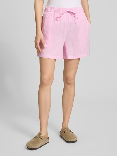 Kobiece model nosi szorty Loose Fit Shorts aus reiner Baumwolle Modell 'AUGUSTA' od Only, efekt: wzór w paski, krój loose fit, tunel, elastyczny ściągacz, wpuszczana kieszeń, materiał: bawełna, różowe odcienie, tekstura miękka, widok całej sylwetki z przodu.