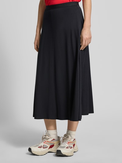 Vrouwenmodel draagt Loose Fit midi-rok uit mix van katoen en lyocell model 'ILENIAA LARAA' van Armedangels, look: effen, fijnrib, labelopschrift op elastische band, midilengte, zijkantaanzicht, detailopname onderlichaam.