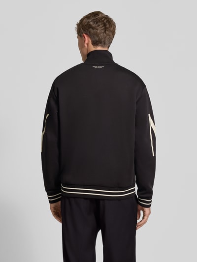 Männermodel trägt schwarze Sweatjacke aus Baumwoll-Mix von Armani Exchange mit Label-Print, lockerer Passform, Rückenansicht.