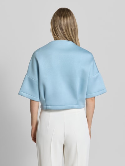 Frauenmodel trägt Jacke mit 1/2-Arm und Reißverschlusstaschen von Rinascimento in Hellblau, glatte Textur, gerader Schnitt, Ganzkörperansicht Rückansicht.