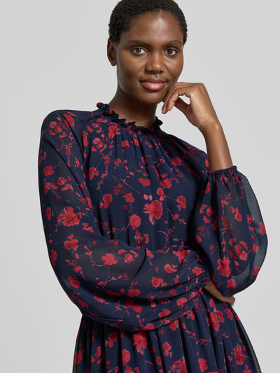 Frauenmodel trägt Midikleid mit Rüschenkragen und Raglanärmeln von Christian Berg Woman Selection in Dunkelblau mit roten Blüten, semitransparente Ärmel, taillierter Schnitt, Nahaufnahme Oberkörper.