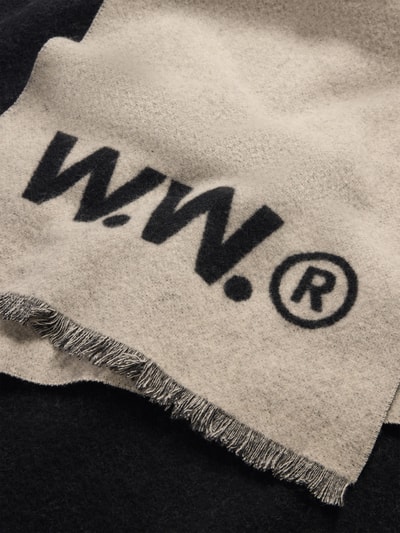 Produktfoto, Schal aus reiner Wolle Modell 'Jackson' von Wood Wood, prostokątny kształt, frędzle, detal z logo, kolor beżowy z czarnym nadrukiem, tekstura miękka, szerokość w rozmiarze 1: 41 cm, długość w rozmiarze 1: 204 cm