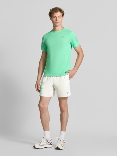 Mężczyzna model prezentuje Regular Fit Shorts mit integriertem Slip Modell 'ICON' od ASICS TIGER, jasne kolory, nadruk z logo, elastyczny pas, Szerokość w rozmiarze M: 37 cm, Długość wewnętrzna nogawki w rozmiarze M: 18 cm, krój regular fit, Ganzkörperansicht von vorne.