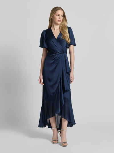 Frauenmodel trägt Cocktailkleid in Wickel-Optik mit V-Ausschnitt von Lipsy in Dunkelblau, Satin, Maxikleid mit Volantsaum, taillierter Schnitt, blickdichtes Unterkleid, Ganzkörperansicht von vorne.