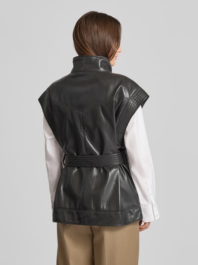 Frauenmodel trägt Regular Fit Weste mit Viskose-Anteil Modell 'JACARO' von BOSS Orange in Schwarz, Kunstleder, Gürtelschlaufen, Ganzkörperansicht Rückansicht.