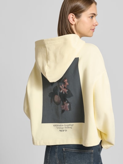 Frauenmodel trägt Boxy Fit Hoodie aus reiner Baumwolle von Marc O'Polo in Hellgelb mit floralem Print, Ganzkörperansicht Rückansicht, Damen Hoodie von Marc O'Polo DENIM.