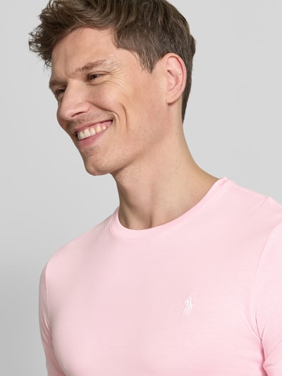 Mannelijk model draagt Regular Fit T-Shirt aus reiner Baumwolle van Polo Ralph Lauren in effen lichtroze jersey met logo-stitching, ronde hals, korte mouw, heren T-shirt, nahaufnahme bovenlichaam.