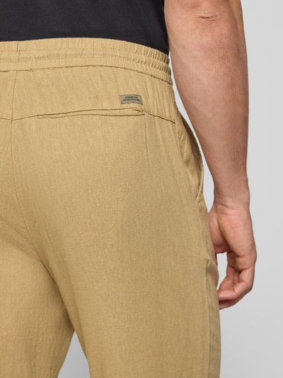 Mężczyznamodel nosi Wide Fit Leinenhose mit Viskose-Anteil Modell 'Malvin' von Blend, kolor beżowy, bawełniana faktura, gumka w pasie oraz kieszeń tylna, szerokość w rozmiarze M: 38 cm, długość nogawki wewnętrznej w rozmiarze M: 76 cm, widok z tyłu zbliżenie na biodra