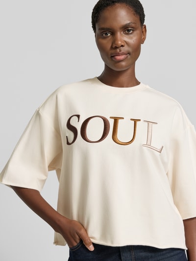 Frauenmodel trägt Cropped Boxy Fit Sweatshirt mit Label-Stitching von Smith and Soul, cremefarben, Rundhalsausschnitt, Detailaufnahme Oberkörper, Damen Baumwoll-Elasthan-Mix, 1/2-Arm.