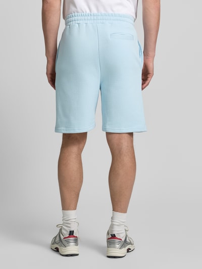 Männermodel trägt Regular Fit Shorts mit Tunnelzug von COLUCCI aus gewachster reiner Baumwolle in Hellblau, Label-Stitching, Ganzkörperansicht Rückansicht