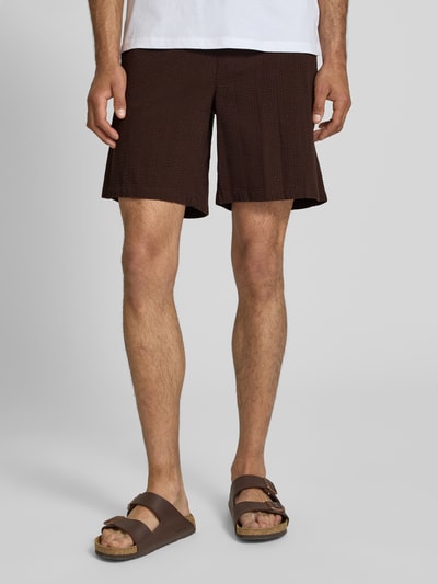 Männermodel trägt Loose Fit Shorts aus reiner Baumwolle Modell 'CRUZ' von Only & Sons, Optik: Unifarben, Materialverarbeitung: Seersucker, seitliche Eingrifftaschen, Gesäßtasche, elastischer Bundabschluss, Verschluss: Tunnelzug, Farbe Dunkelbraun, Ganzkörperansicht von vorne.