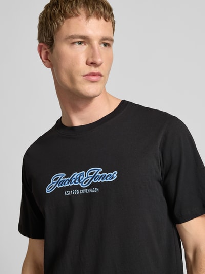 Männermodel trägt Regular Fit T-Shirt mit Logo-Print von JACK & JONES aus reiner Baumwolle, Rundhalsausschnitt, Nahaufnahme Oberkörper.