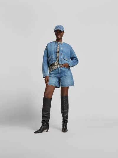 Frauenmodel trägt Jeansshorts aus reiner Baumwolle von Anine Bing in A-Linie mit 5-Pocket-Design, Knopf- und Reißverschluss, Kontrastnähten, mittlerem Blau, Ganzkörperansicht von vorne.