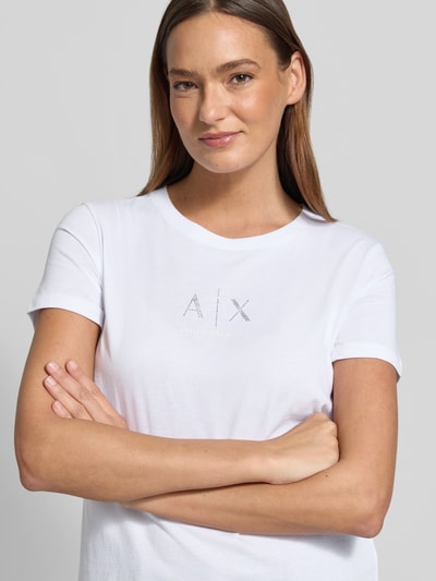 Vrouwenmodel draagt T-shirt met ronde hals en logo van Armani Exchange in wit, puur katoen, regular fit, ruglengte maat S: 62 cm, close-up bovenlichaam.