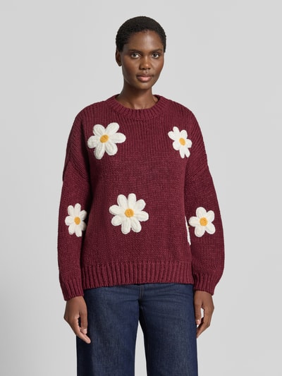Männermodel trägt Oversized Strickpullover mit floralen Stitchings von Apricot, okrągły dekolt, prążkowane wykończenia, kolor bordowy, Długość tyłu 62 cm, Długość rękawów 43 cm, Ganzkörperansicht von vorne.