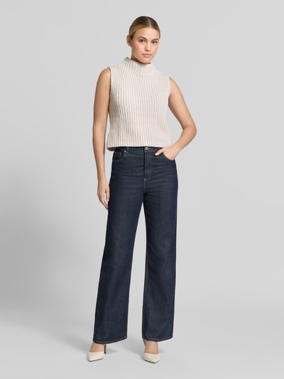Frauenmodel trägt Regular Fit Top in Strick-Optik von monari in Beige, ärmellos, Stehkragen, kombiniert mit Jeans, Ganzkörperansicht von vorne, Rückenlänge bei Größe 36: 51 cm.