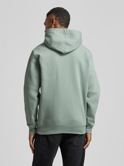 Männermodel trägt Sweatjacke mit Logo und Känguru-Tasche von GAP in hellem Grün, Baumwoll-Mix, Regular Fit, Ganzkörperansicht Rückansicht.