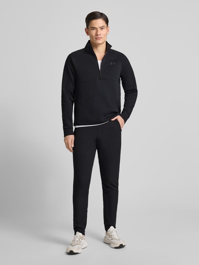 Männermodel trägt Sweatshirt mit Stehkragen von Under Armour, schwarz, Baumwoll-Materialmix, Label-Print, Ganzkörperansicht von vorne.