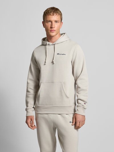 Männermodel trägt Hoodie mit Kapuze von CHAMPION in Beige, Baumwoll-Mix, Lockerer-Schnitt, Label-Stitching, Känguru-Tasche, Nahaufnahme Oberkörper.