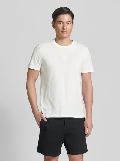Männermodel trägt T-Shirt mit Rundhalsausschnitt und Label-Stitching von GAP in Weiß, Regular Fit, reine Baumwolle, Ganzkörperansicht von vorne.