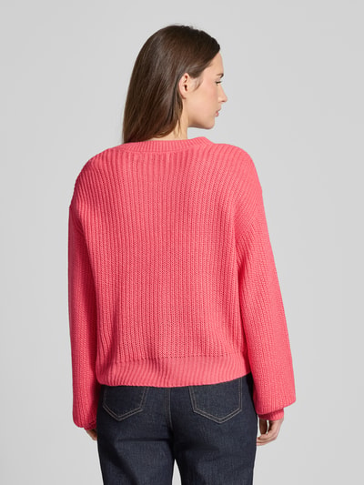 Vrouwenmodel draagt Regular Fit Strickjacke met eenrijige knoopsluiting model 'LEA' van Vero Moda, effen roze breisel, ribboorden, long sleeves, achteraanzicht volledige lengte.