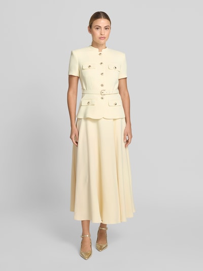 Frauenmodel trägt Maxikleid mit Stehkragen von Self-Portrait in Creme, taillierte Passform, Pattentaschen, abnehmbarer Tailliengürtel, Kurzärmelig, glatte Struktur, Ganzkörperansicht von vorne.