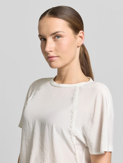 Frauenmodel trägt Relaxed Fit Bluse mit Zierbesatz von Luisa Cerano in Offwhite, leicht strukturierte Oberfläche, Nahaufnahme Oberkörper.