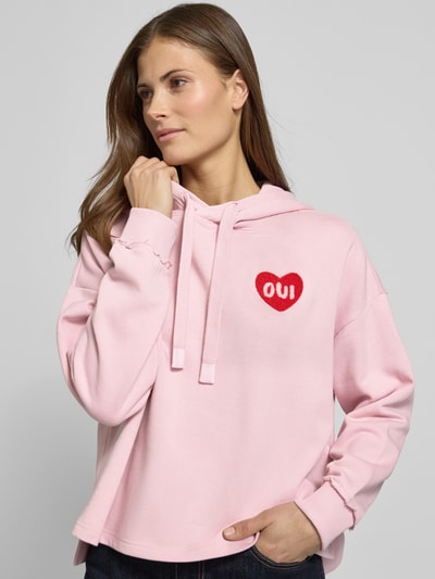 Frauenmodel trägt Hoodie mit Kapuze von Oui in Rosa aus Baumwoll-Mix, Lockerer-Schnitt, Kapuze, Tunnelzug, Label-Detail, gerippte Ärmelabschlüsse, Nahaufnahme Oberkörper.
