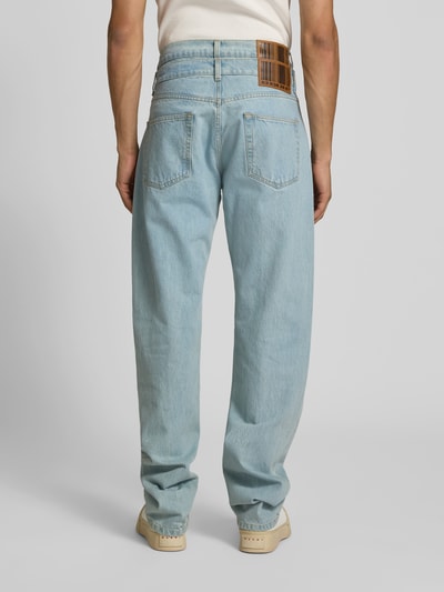 Männermodel trägt Regular Fit Jeans mit Label-Detail von VETEMENTS in hellblauer Reine Baumwolle, 5-Pocket-Design, Ganzkörperansicht Rückansicht.