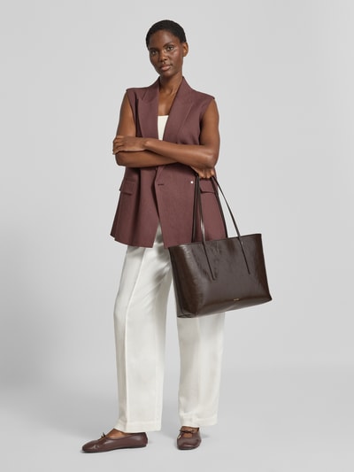 Kobiece modelka nosi Henkeltasche mit Label-Detail od CK Calvin Klein, ciemnobrązowa, gładka powierzchnia, Ganzkörperansicht von vorne.