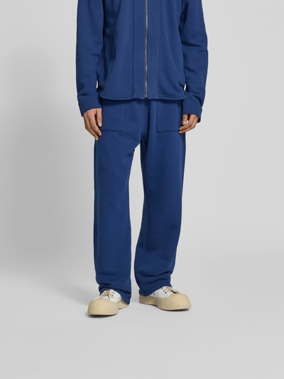 Männermodel trägt Straight Fit Sweatpants mit Logo-Detail von Kenzo aus reiner Baumwolle in Blau, aufgesetzte Taschen, Nahaufnahme Unterkörper.