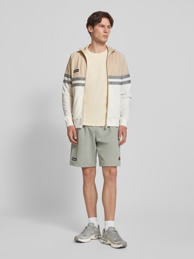 Männermodel trägt Trainingsjacke mit Label-Patch und Stehkragen Modell 'RIMINI' von ellesse aus Baumwoll-Mix, Regular-Fit, Ganzkörperansicht von vorne.