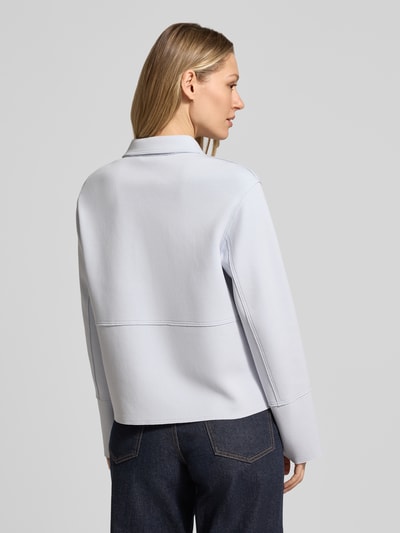 Modelka nosi żakiet 'Blazer mit Kentkragen und aufgesetzten Pattentaschen' od WHITE LABEL, mieszanka bawełny z dodatkiem streczu, prosty krój, kołnierzyk typu kent, zapięcie kryte, kieszenie z patką, długość tyłu w rozmiarze 36: 57 cm, szerokość w rozmiarze 36: 51 cm, długość rękawów w rozmiarze 36: 61 cm, jasny kolor, gładka tekstura, całkowity widok od tyłu.