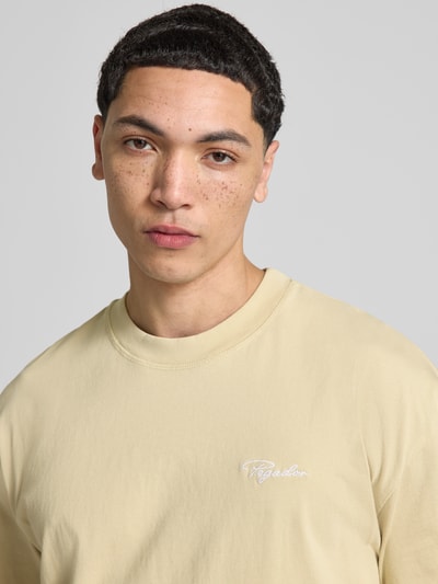 Männermodel draagt Oversized Fit T-shirt mit logo-stitching van Pegador in lichtgeel, puur katoen, ronde hals, ruglengte maat M 71 cm, nahaufnahme oberkörper.