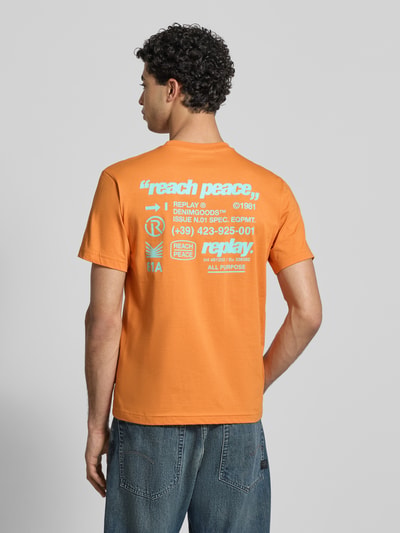 Mężczyznęmodel nosi Regular Fit T-Shirt mit Statement-Print von Replay z czystej bawełny, pomarańczowy, okrągły dekolt, długość tyłu w rozmiarze M: 62 cm, widok całej sylwetki z tyłu.