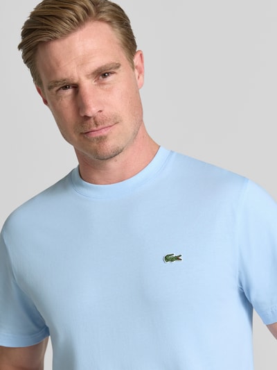 Männermodel trägt Regular Fit T-Shirt aus reiner Baumwolle von Lacoste in Hellblau, glatte Textur, Herren T-Shirt, Nahaufnahme Oberkörper.
