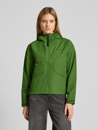 Vrouwenmodel draagt Jacke met Pattentaschen model 'MILENA' van Didriksons in recht pasvorm en capuchon, labelprint, voorkantaanzicht.