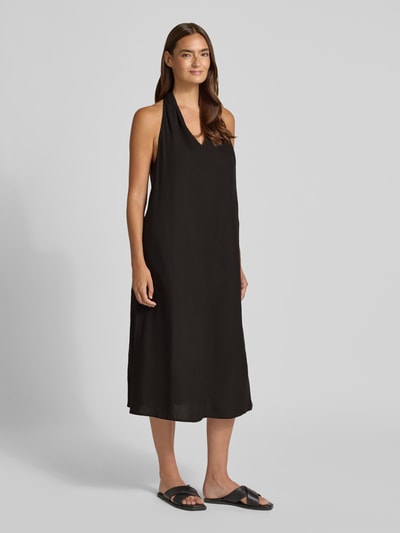 Frauenmodel trägt schwarzes Midikleid aus Viskose-Mix mit Leinen-Viskose-Anteil, V-Ausschnitt, Neckholder, Loose-Fit, Modell 'Qudia' von Someday, seitlicher Nahtreißverschluss, Ganzkörperansicht von vorne. Damen Midikleid, Rückenlänge bei Größe 36: 116 cm, Brustweite: 48 cm.
