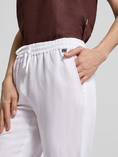 Männermodel trägt Straight Fit Stoffhose aus Viskose-Mix mit Leinen-Anteil von Marc Cain, biała, elastyczny pas, kieszenie, krój straight fit, Szerokość w rozmiarze 36: 37 cm, długość nogawki 66 cm, wygląd lnu, zdjęcie w zbliżeniu na górną część spodni, z boku