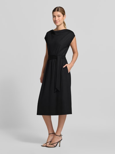 Modelka kobieca ma na sobie czarne Relaxed Fit Freizeitkleid aus Viskose-Mix od s.Oliver BLACK LABEL, gładka tkanina, widok całej sylwetki z przodu.
