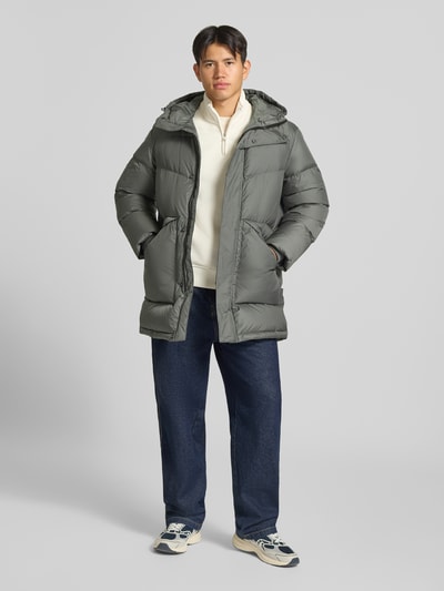 Männermodel trägt Regular Fit Steppmantel mit Kapuze von Marc O'Polo DENIM in Grau, strukturierte Oberfläche, Ganzkörperansicht von vorne.