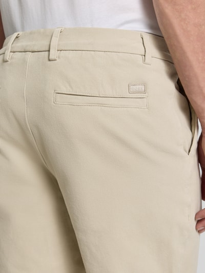 Männermodel trägt Modern Fit Chinoshorts aus Baumwoll-Mix Modell 'KANE1' von BOSS in Beige, feine Textur, Nahaufnahme Rückansicht. Herren Chinoshorts, unifarbene Optik, seitliche Eingrifftaschen, Paspeltaschen, Knopfverschluss.