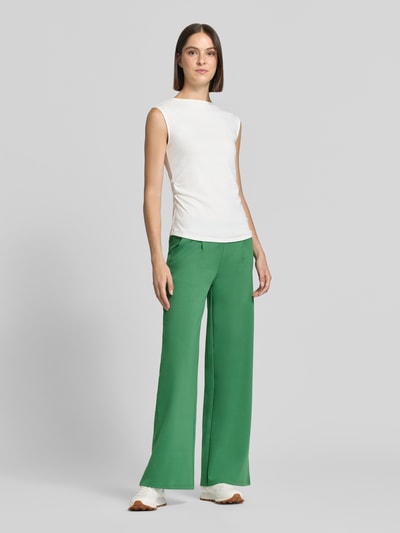 Frauenmodel trägt Wide Fit Hose mit Viskose-Anteil Modell 'Kate' von ICHI in Grün, elastischer Material-Mix, Ganzkörperansicht von vorne.