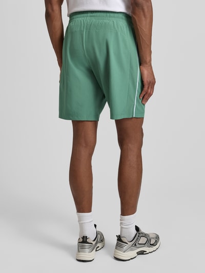 Männermodel trägt Shorts mit elastischem Bund und Logo von EA7 Emporio Armani in Grün, Material-Mix, Regular Fit, Ganzkörperansicht Rückansicht.