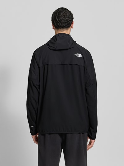 Męski model nosi Jacke mit Logo und Reißverschluss von The North Face, czarna mieszanka materiałów z dodatkiem streczu, krój regular fit, logo, kaptur, zamek błyskawiczny, długość tyłu w rozmiarze M: 63 cm, szerokość ramion w rozmiarze M: 48 cm, szerokość klatki piersiowej w rozmiarze M: 33 cm, długość rękawów w rozmiarze M: 65 cm, widok całej sylwetki z tyłu.