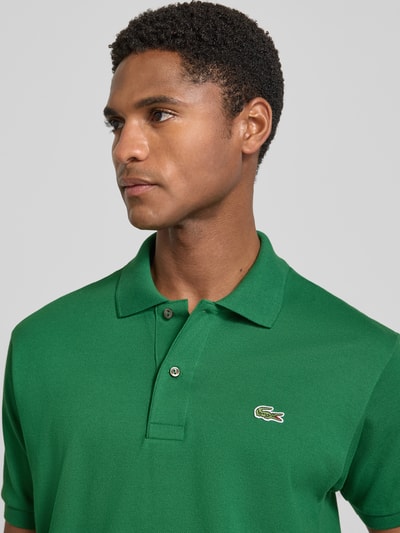 Mężczyzna nosi koszulkę polo Regular Fit Poloshirt aus reiner Baumwolle Modell 'CORE' von Lacoste, zielony kolor, tekstura pikowana, Herren Poloshirt von Lacoste, zbliżenie na górną część ciała