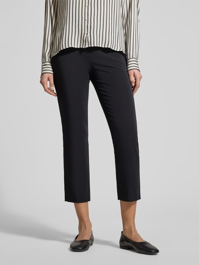 Kobieta nosi Schmale Schlupfhose aus Techno Cotton Superstretch od Raffaello Rossi, krój slim fit, czarny, model 'PENNY 6/8', szerokość w rozmiarze 36: 36 cm, długość nogawki wewnętrznej w rozmiarze 36: 61 cm, ujęcie całej sylwetki z przodu.