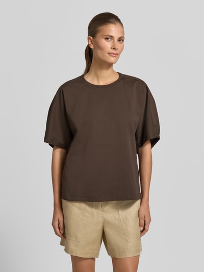Modelka kobieca ma na sobie brązowy T-Shirt z okrągłym dekoltem, model 'CELLULA' od MM by Max Mara, czysta bawełna, krój relaxed fit, długość tyłu w rozmiarze S: 59 cm, krótkie beżowe szorty, gładka faktura, pełny widok z przodu.